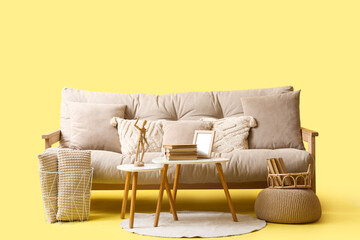 Comfortable white sofa and coffee table with books on yellow background