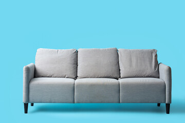 Comfortable grey sofa on blue background