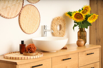 Vase with beautiful sunflowers on wooden cabinet in bathroom