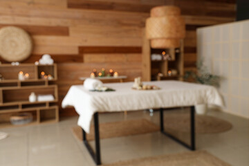 Blurred view of stylish spa salon with couch, burning candles and wooden furniture
