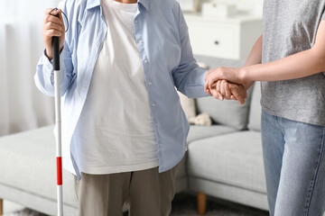 Young woman with blind grandmother walking at home, closeup