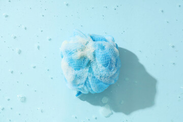 Bath sponge with soap foam in water on color background