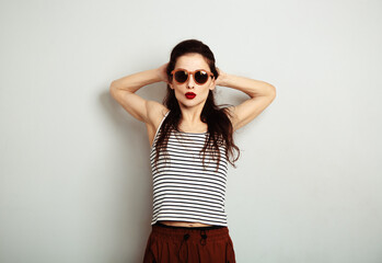 Fun relax smiling woman posing in fashion sunglasses and stripped t-shirt with red lipstick on white wall background with empty copy space. Happy fashion lifestyle