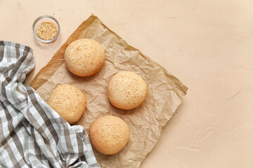 Baking paper of fresh buns with sesame seeds on beige background