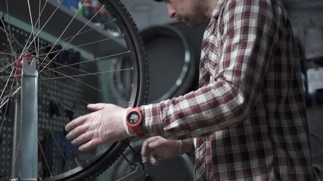Working alignment of rim and spokes of bicycle wheel on wheel stand in bike repair shop. Bike repairman with specialized tool in workshop tightening wheel spokes. Cycle mechanic fixes wheel. 