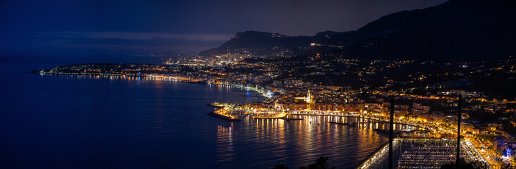 Night view on French Riviera, lights of Menton old city and marina on blue Mediterranean Sea near...