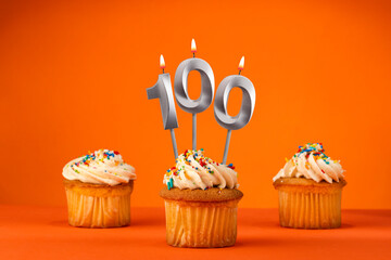 Candle number 100 - Celebration with birthday cupcake on orange background