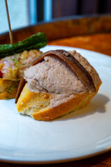 Typical snacks of Basque Country, pinchos or pinxtos skewers with small pieces of bread, fish, sea food, sweet green pepper served in bar in San-Sebastian or Bilbao, Spain