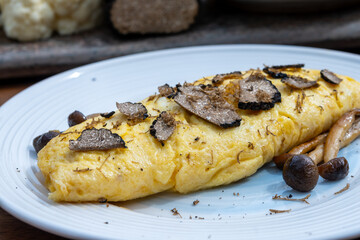 French omelette with mushrooms, fresh farmers eggs and black summer truffle mushroom in pieces for making truffle dishes with tasty aroma