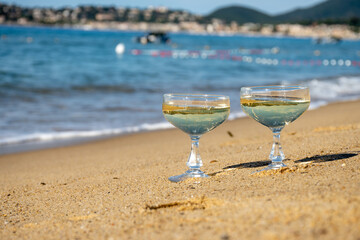 Summer time on French Riviera, two coupe glasses of champagne cremant sparkling wine on Pampelonne sandy beach near Saint-Tropez in sunny day, Var, vacation in France