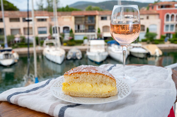 Wine and cakes of French Riviera, glasses of cold rose Cote de Provence wine and Tarte Tropezienne cake in yacht harbour of Port Grimaud, summer vacation in Provence, France