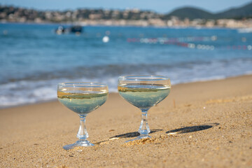 Summer time on French Riviera, two coupe glasses of champagne cremant sparkling wine on Pampelonne sandy beach near Saint-Tropez in sunny day, Var, vacation in France