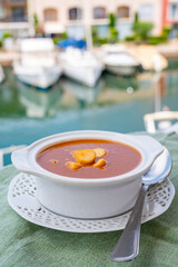 Homemade tasty fish or bisque soup with croutons and view on yacht boats and houses of Port...