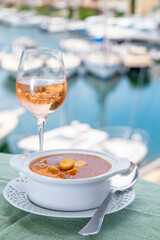 Homemade tasty fish or bisque soup with croutons served with glass of cold rose wine and view on yacht boats and houses of Port Grimaud, French Riviera, France. Food of Provence