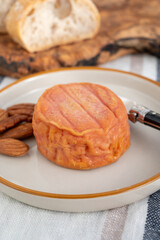 Rond des Vignes washed-rind cheese with.ivory-orange rind, strong nose with aromas, French soft cheese with orange rind