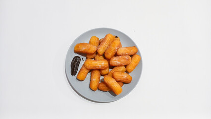 Churros sticks in a small plate with white powdered sugar and a bowl of chocolate sauce