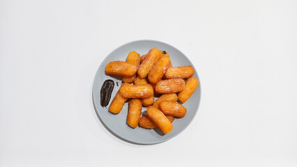 Churros sticks in a small plate with white powdered sugar and a bowl of chocolate sauce