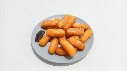 Churros sticks in a small plate with white powdered sugar and a bowl of chocolate sauce