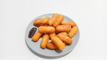 Churros sticks in a small plate with white powdered sugar and a bowl of chocolate sauce