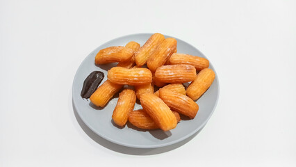 Churros sticks in a small plate with white powdered sugar and a bowl of chocolate sauce