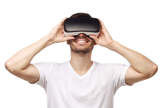 Young smiling man wearing t-shirt and virtual reality headset or VR glasses, playing video game