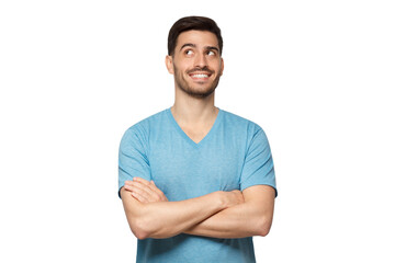 Portrait of young handsome guy wearing blue t-shirt standing with crossed arms, looking up and smiling with curious face