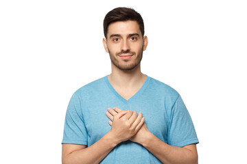 Fototapeta premium Kind hearted friendly nice guy shows kindness, wearing blue t-shirt. Smiling positive young man keeps hands on chest