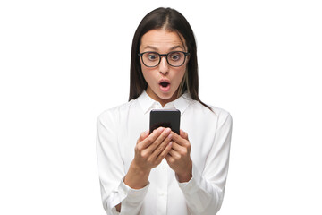 Young woman with shocked face staring at screen of her phone, dressed in white shirt