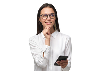 Young woman making plans while holding phone in hand and looking to right side through glasses