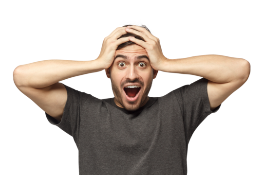 Emotional young man with round eyes, open mouth and hands pressed to top of head, showing astonishment and shock
