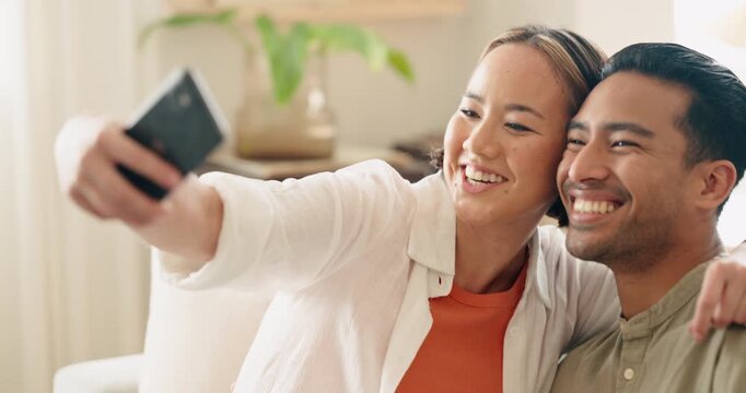 Asian couple, phone and sofa selfie in house or home living room for social media technology, profile picture or memory. Smile, happy and bonding man or woman in fun, trust or love mobile photography