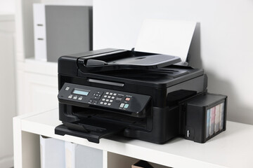Modern printer with paper on table in office