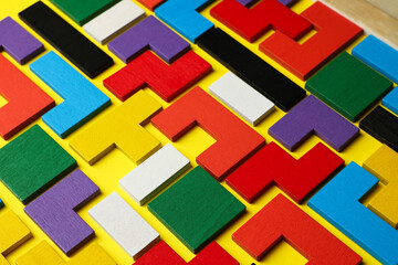 Colorful wooden puzzle pieces on yellow background, closeup
