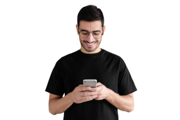 Young man standing against, looking at screen of phone, browsing web and smiling nicely while chatting