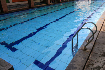 Obraz premium A picture of a swimming pool with clear blue water, a metal ladder, and black lane lines. Swimming Pool with Clear Blue Water Background.