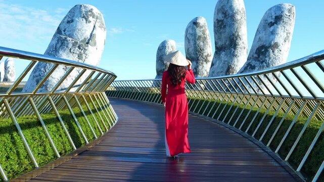 4k slow motion,Asian woman wearing red.Vietnamese culture with traditional conical hat withon the Golden han Bridge, Da Nang City, Vietnam.