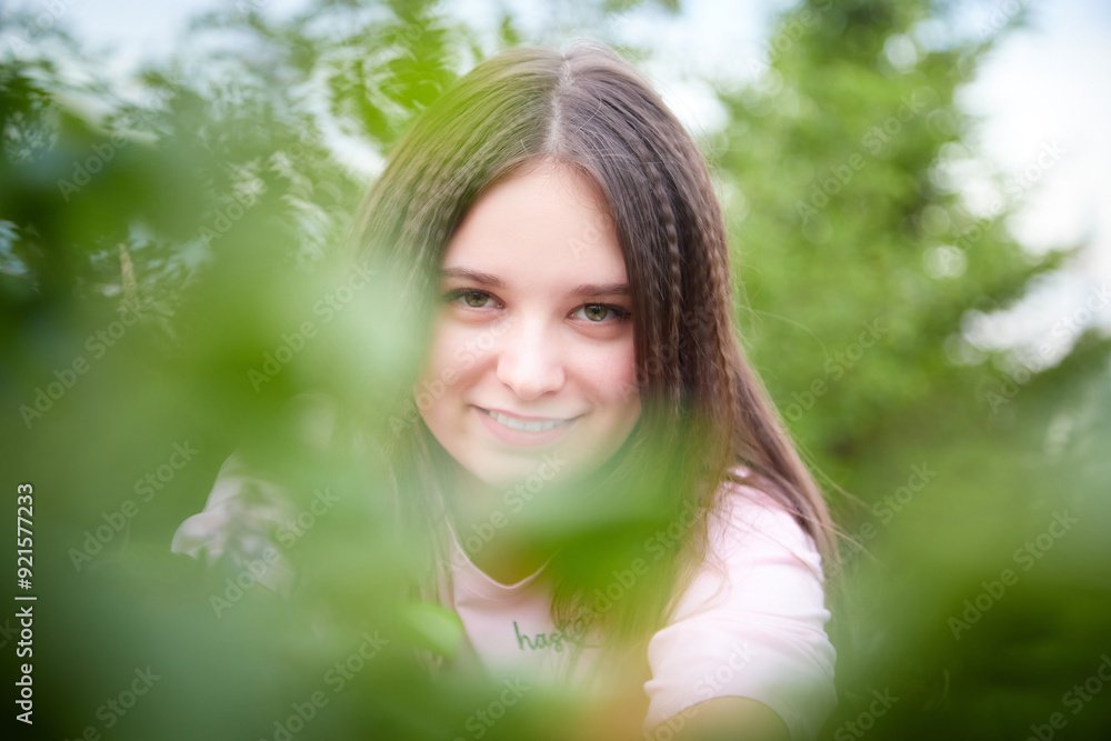 Wall mural portrait of young pretty woman with long brown hair in greenery