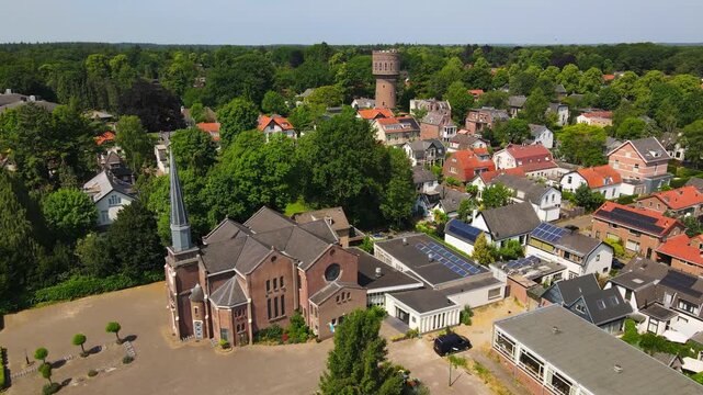 An aerial view of Paaskerk Church in Baarn, Netherlands, highlighting the charming residential area and lush greenery surrounding this historic church.