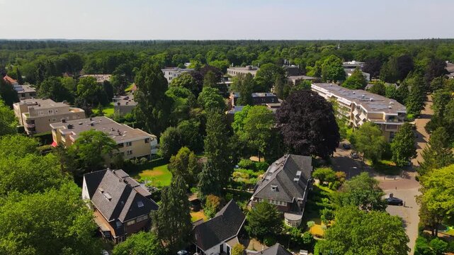 A serene aerial view of Baarn, Netherlands, highlighting a peaceful residential area surrounded by lush greenery and tree-lined streets, capturing the town's tranquil atmosphere.