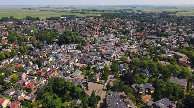 Aerial view of Baarn, Netherlands, showcasing the charming blend of residential homes, greenery, and small-town commercial areas with a clear view of the surrounding landscape.