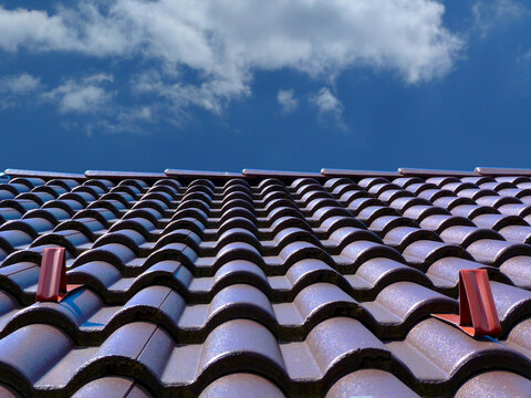 sloped dark brown clay tile roof and ridge. construction, modern building materials and technology concept. blue sky and fluffy white cloud. bright summer light. low angle abstract view