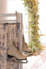 Vintage white figure skates hanging on a wall. Female winter hobby and activity. Old pair of shoes...