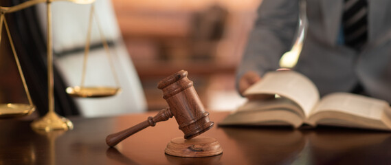 Gavel and Scales of Justice with Civil law notary or lawyer reading law book for legal services and advice.