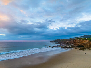 Sunrise Seascape with beautiful cloud covered sky and gentle surf