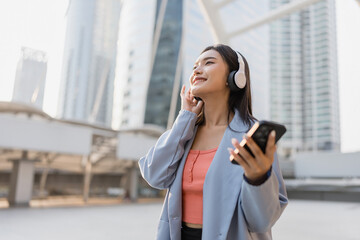 Asian woman wearing headphone and using smartphone device in the city. 