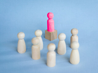Red toy block standing on podium facing other toy blocks on desk. Illustrate leadership concept.