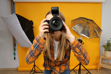 Beautiful girl photographer in the photo studio, on a yellow background.