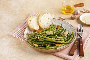Fried green beans with garlic and sesame in a plate on a brown background. vegetarian dish, copy space