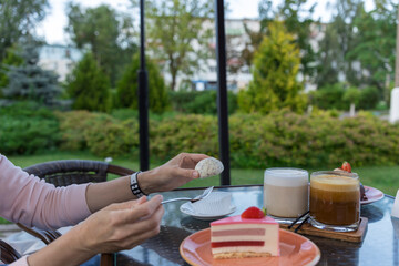 A woman is eating a dessert at a table with a cake and a cup of coffee