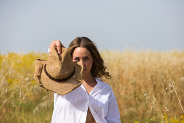 portrait of a beautiful young blonde woman standing in a field of oats. The woman is holding up a...
